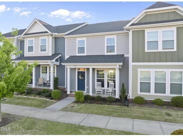 Charming townhome with a blue front door, rocking chairs on the porch and well-maintained landscaping at 6511 Academic Ave, Raleigh, NC 27616