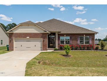 Charming brick home featuring manicured landscaping and a convenient two-car garage at 8 Pal Ct, Benson, NC 27504