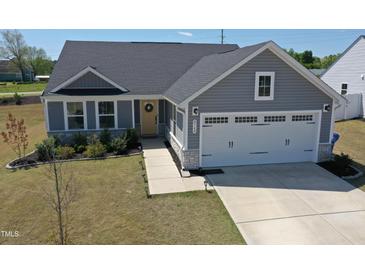 Charming single-Gathering home with a two-car garage, gray siding, and a welcoming front door at 8764 Kenridge Ln, Fuquay Varina, NC 27526