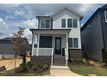 Charming two-story home showcasing a brick foundation, covered porch, and modern architectural design at 10 Relaxing Way, Pittsboro, NC 27312