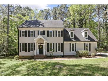 Charming two-story home featuring classic architectural design and a well-manicured front yard with mature trees at 1013 Whitney Springs Ct, Holly Springs, NC 27540