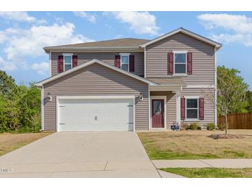 Two-story home with gray siding, white garage door, and red shutters offers classic curb appeal at 217 Braeburn Dr, Graham, NC 27253