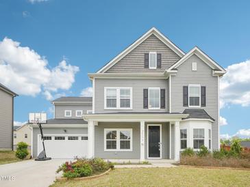 Charming two-story home with gray siding, black shutters, an attached garage and a basketball hoop out front at 2613 Red Spruce Dr, Raleigh, NC 27616