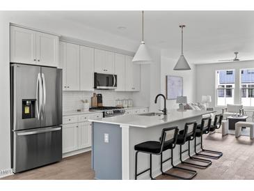 Modern kitchen boasts stainless appliances, a large island with seating, and white cabinets at 6406 Tanner Oak Ln, Raleigh, NC 27613