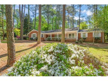 Charming brick home with a welcoming front porch surrounded by lush landscaping and mature trees at 6804 Justice Dr, Raleigh, NC 27615
