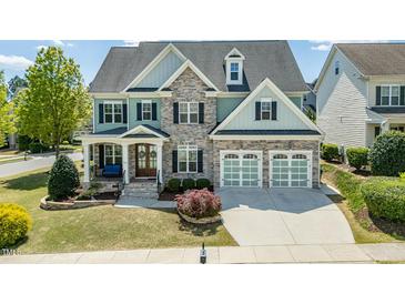 Beautiful two-story home with a stone facade, manicured lawn, and a two-car garage at 7101 Gibson Creek Pl, Cary, NC 27519