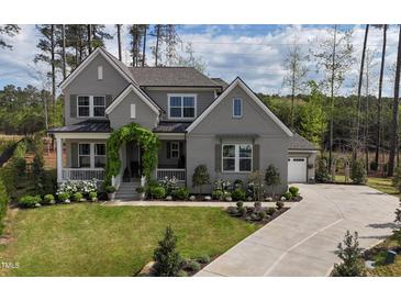 Charming gray two-story home with a lush green lawn and inviting front porch and walkway at 8208 Bella Oak Ct, Wake Forest, NC 27587