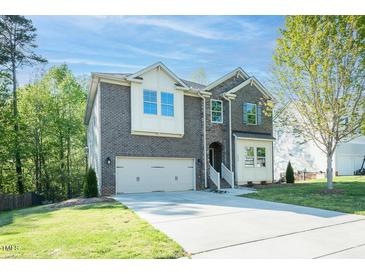 Charming two-story brick home with attached garage, and manicured lawn on a sunny day at 1004 Longleaf Pine Pl, Mebane, NC 27302