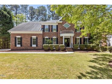 Beautiful brick home featuring manicured lawn, mature trees, classic shutters, and charming entry balcony at 103 Ticonderoga Rd, Cary, NC 27519