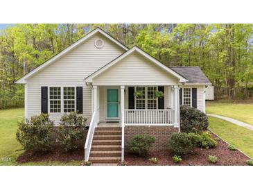Charming home featuring a quaint front porch, a teal door, and meticulously landscaped garden beds at 1106 Lake Ridge Dr, Creedmoor, NC 27522