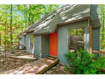 Charming home exterior featuring a modern gray facade, orange front door, and wooden walkway in a wooded setting at 158 Poplar St # A, Chapel Hill, NC 27516