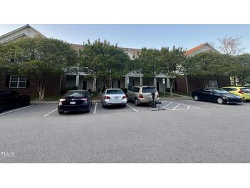 Exterior view of the parking lot in front of the condos and mature trees surrounding at 2124 Claret Ln, Morrisville, NC 27560