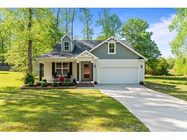 Charming home with a well-maintained lawn, a front porch seating area, and an attached two-car garage at 308 Thorndale Dr, Dunn, NC 28334
