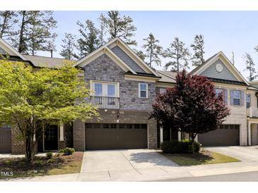Charming townhome featuring a stone and brick facade, two-car garage, and well-manicured landscaping at 317 Castle Rock Ln, Cary, NC 27519