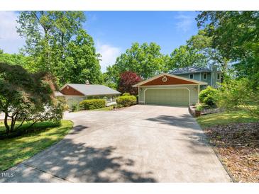 Inviting home featuring a long, private driveway leading to a spacious three car garage, all surrounded by lush landscaping at 373 & 375 Sagamore Dr, Louisburg, NC 27549