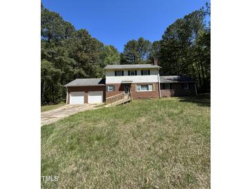 Charming two-story home with a brick exterior and a two-car garage, surrounded by mature trees at 683 Osgood Rd, Sanford, NC 27330