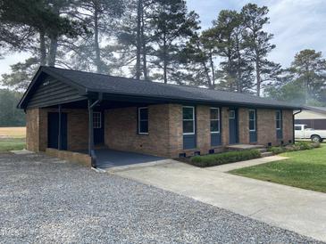 Charming brick home with a covered carport, well-maintained lawn, and mature trees at 83 Brentwood Dr, Selma, NC 27576