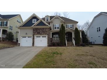 Beautiful two-story home with stone accents, a covered porch, and a well-manicured lawn at 901 Hollymont Dr, Holly Springs, NC 27540