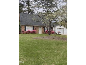 Charming brick home featuring blooming pink azaleas and a detached garage at 1408 Edgebrook Dr, Garner, NC 27529