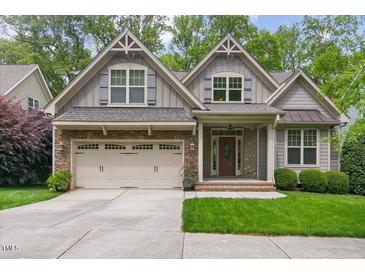 Charming home featuring a stone facade, gray siding, a well-manicured lawn, and an attached two-car garage at 144 Cobble Ridge Dr, Pittsboro, NC 27312