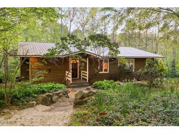 Charming home exterior with wood siding, metal roof, and beautifully landscaped front yard at 195 Nicks W Bnd, Pittsboro, NC 27312