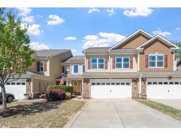 Charming two-story townhome with an attached two car garage and an inviting facade with red shutters at 225 Mayfield Dr, Apex, NC 27539