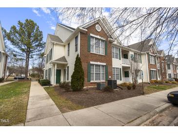 Inviting townhome exterior with brick accents, green shutters, well-maintained landscaping, and sidewalk access at 2421 Kudrow Ln, Morrisville, NC 27560