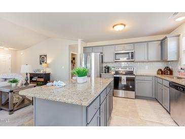Bright kitchen boasts granite counters, stainless appliances, tile backsplash and center island at 25 Cornfield Ln, Benson, NC 27504