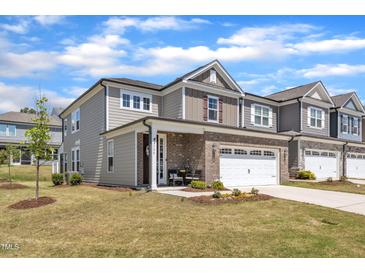 Charming two-story home with a brick and gray siding facade, well-manicured lawn, and attached two-car garage at 2528 Forge Village Way, Apex, NC 27523