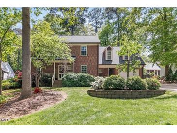 Charming brick home with a landscaped front yard, mature trees, and a welcoming front porch at 3117 Woodgreen Dr, Raleigh, NC 27607