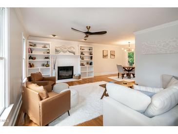 Bright living room with a fireplace, built-in shelving, plush rug, and wood flooring at 3317 E Jameson Rd, Raleigh, NC 27604