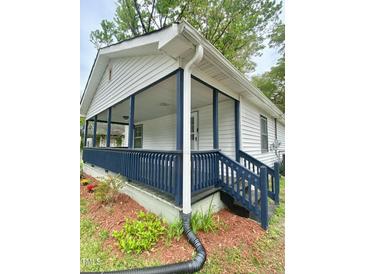Charming home featuring a cozy front porch with blue accents and a well-maintained exterior at 409 Neathery St, Henderson, NC 27536