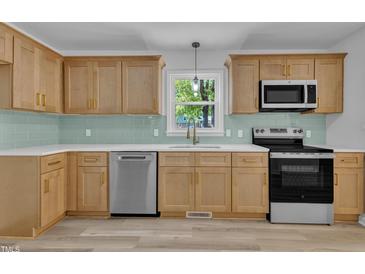 Bright kitchen features updated cabinets, stainless appliances, light countertops, and subway tile backsplash at 419 Joy Dr, Garner, NC 27529