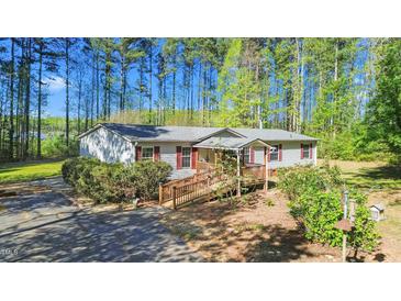 Charming one-story home features a sloped wooden ramp, complemented by lush landscaping and tall trees at 4500 Governor Hunt St, Efland, NC 27243