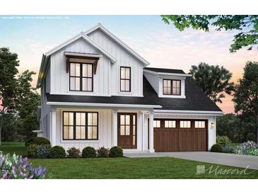 Charming two-story modern farmhouse with a black roof, a well-manicured lawn, and a two car garage at 5491 Silk Hope Gum Springs Rd, Siler City, NC 27344