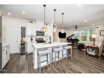 Modern kitchen with white cabinets, a center island with seating, and stainless steel appliances at 1403 Chipping Dr, Apex, NC 27502
