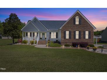 Charming two-story home showcasing a landscaped yard, brick accents, and inviting front porch at twilight at 192 Ash Lily Ct, Nashville, NC 27856