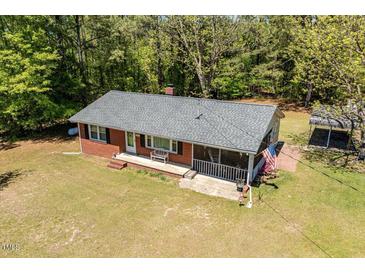 Charming brick home with a screened-in porch, bench, and an American flag in a wooded setting at 19461 Nc Highway 210, Angier, NC 27501