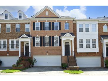 Brick townhome featuring symmetrical design, black shutters, and inviting front entrance with garage at 2507 Princewood St, Raleigh, NC 27612