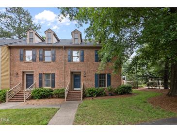 Charming brick townhome with dormer windows, a quaint entrance, and lush green landscaping at 3100 Coachmans Way, Durham, NC 27705