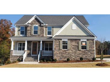 Beautiful two-story home featuring stone accents, shuttered windows, and an inviting front porch at 33 Blackhorn Ct, Pittsboro, NC 27312