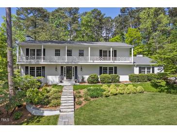 Beautiful two-story home with a white brick facade, well-manicured lawn, and a charming balcony at 3826 Regent Rd, Durham, NC 27707