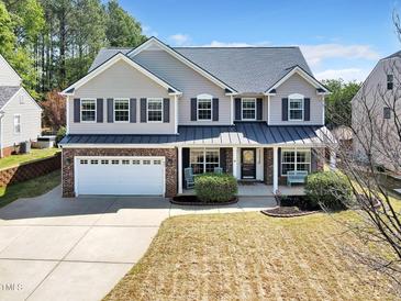 Charming two-story home with a well-manicured lawn and a two-car garage at 421 Gooseberry Dr, Holly Springs, NC 27540