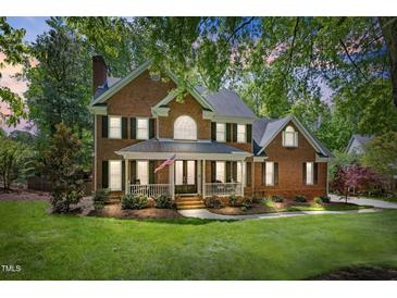Charming red brick two-story home with a welcoming front porch and well-maintained landscaping at 4513 Touchstone Forest Rd, Raleigh, NC 27612