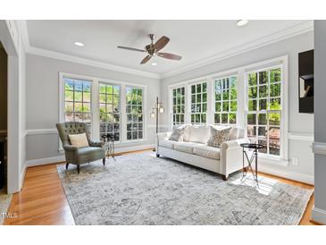 Sun-filled living room featuring a comfortable couch, accent chair, and large windows overlooking the backyard at 4513 Touchstone Forest Rd, Raleigh, NC 27612