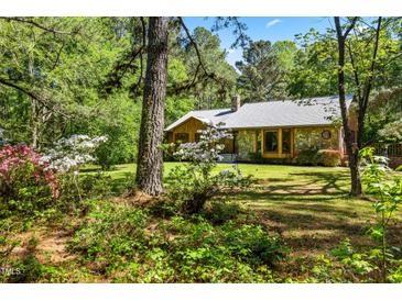 Charming stone and wood home nestled in a lush, wooded lot with flowering bushes at 5204 William And Mary, Raleigh, NC 27616