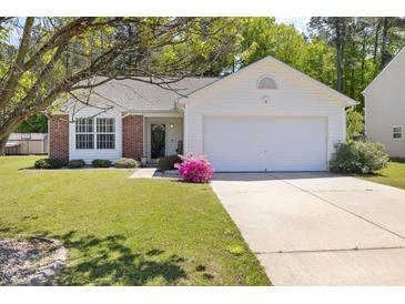 Charming home with brick accents, a well-manicured lawn, and a driveway leading to a two-car garage at 729 Golden Horseshoe Ln, Sanford, NC 27330