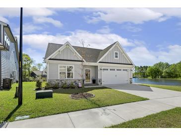 Beautiful single-Gathering home with a well-manicured lawn, attached garage and water view at 98 Buddy Campbell Ct, Angier, NC 27501