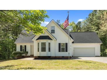 Charming white home featuring an American flag, bay window, manicured lawn, and attached garage at 105 Coral Ridge Cir, Franklinton, NC 27525