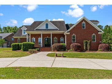Stately brick home featuring a covered front porch, manicured landscaping, and a spacious driveway at 121 Westchase Run, Sanford, NC 27330